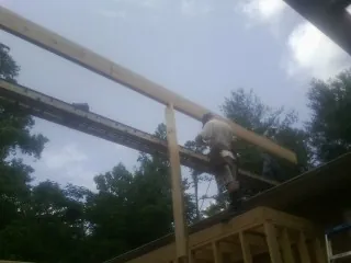 Carpenter setting a ridge beam over a new addition frame — Ice Dam Removal by Roofing Brothers in Clark Fork