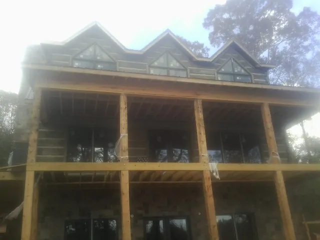 Dormers and porch framing on a large log home under construction — Roof Coating work by our crew in Clark Fork