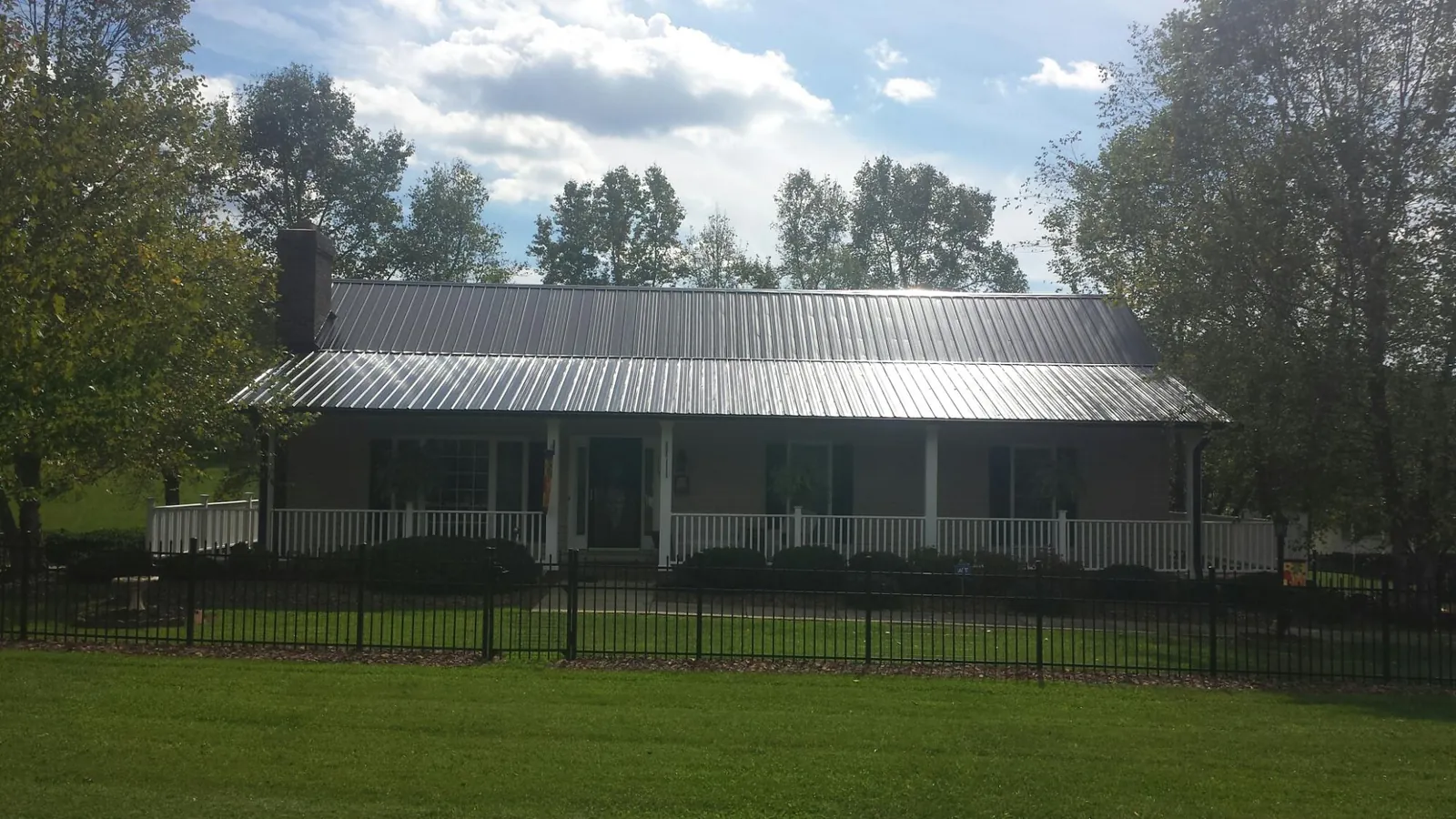 Gray metal roof on a brick ranch with a full width front porch — Gutter Guard Installation work by our crew in Clark Fork