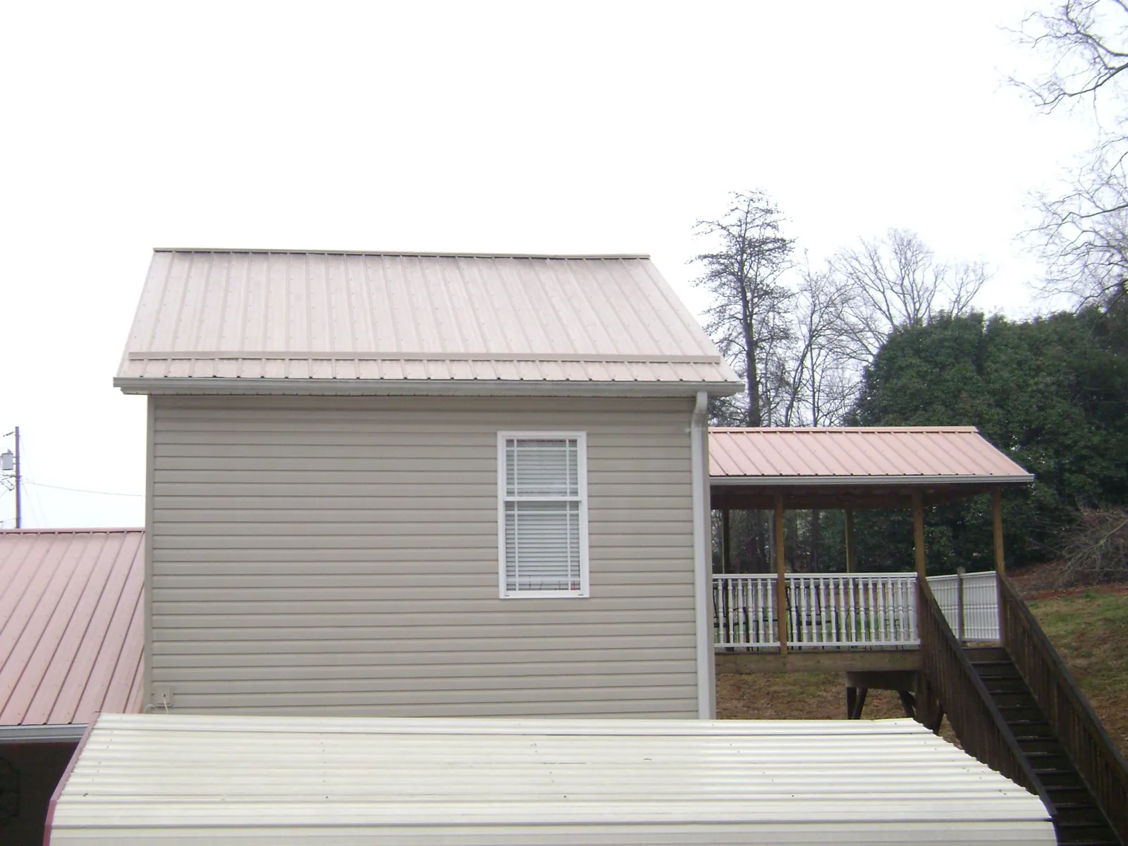 Tan metal roofs on a two story addition and attached porch, from a Roof Replacement job in Clark Fork