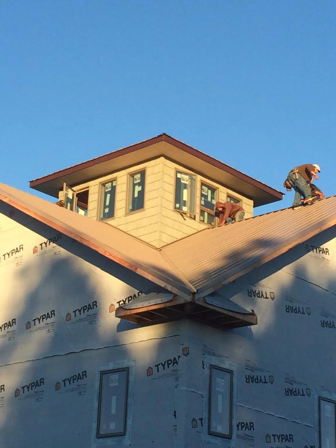 Roofers working around a rooftop cupola on a new metal roof at sunset — Roof Waterproofing in Clark Fork by Roofing Brothers
